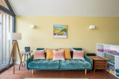 a living room with a green couch with pillows at Sedge House, Eastbridge, Close to the coast, RSPB Nature Reserve, Dunwich, Sizewell and Leiston - Managed by Aldeburgh Coastal Cottages in Theberton