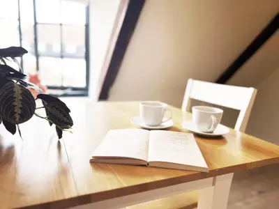 an open book on a table with two cups and a plant at Carleys Yard by The Suffolk Cottage Collection in Framlingham