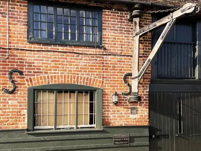a crane is attached to the side of a brick building at Carleys Yard by The Suffolk Cottage Collection in Framlingham