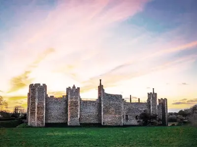 an old castle with a sunset in the background at Carleys Yard by The Suffolk Cottage Collection in Framlingham