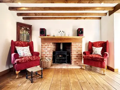 a living room with two chairs and a fireplace at Brick Kiln Holdings by The Suffolk Cottage Collection in Badingham