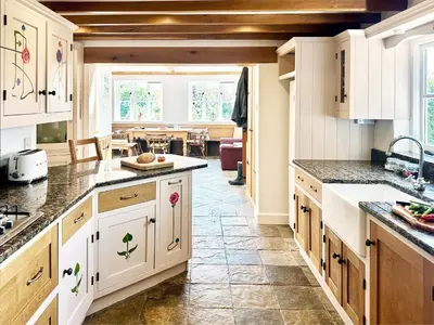 a kitchen with white cabinets and a dining room at Brick Kiln Holdings by The Suffolk Cottage Collection in Badingham