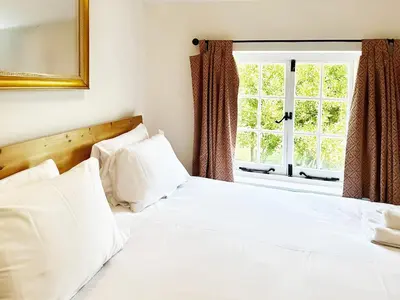 a bedroom with a white bed with a window at Brick Kiln Holdings by The Suffolk Cottage Collection in Badingham