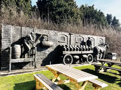 a stone wall with a statue of a man driving a wagon at Blackberry Barn by The Suffolk Cottage Collection in Long Melford