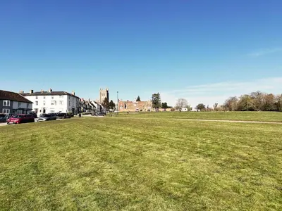 a large field of grass with buildings in the background at Blackberry Barn by The Suffolk Cottage Collection in Long Melford