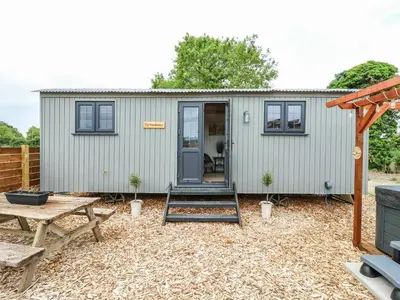 a tiny house with a door and a table at Luxury Shepherd Hut with Private Hot Tub in Swaffham Bulbeck