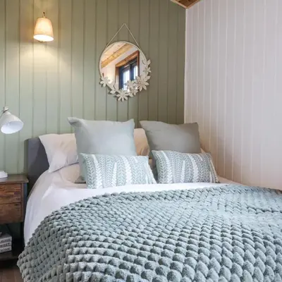 a bedroom with a large bed and a mirror at Luxury Shepherd Hut with Private Hot Tub in Swaffham Bulbeck