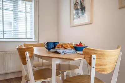 a dining room table with chairs and a table with bread at 19BC, Aldeburgh in Aldeburgh