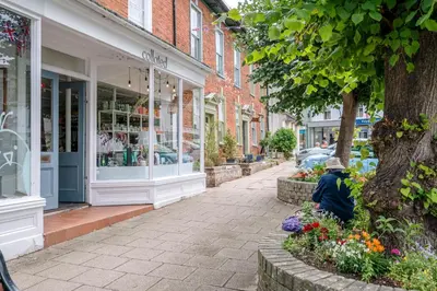 a person sitting on a sidewalk in front of a store at Market View, Framlingham in Framlingham