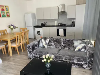 a living room with a couch and a table and a kitchen at Stylish 3 Bed Seaside Apartment Central Southend Location & Steps from the Beach in Southend-on-Sea