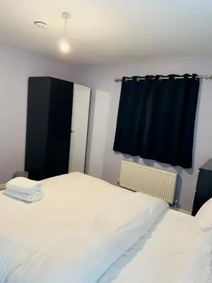 a bedroom with two beds and a black curtain at Cosy and Bright Stay Ipswich in Ipswich