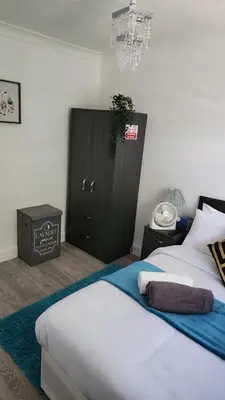 a bedroom with two beds and a black cabinet at Luxurious ensuite rooms in Basildon