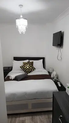 a bedroom with a large bed with a chandelier at Luxurious ensuite rooms in Basildon