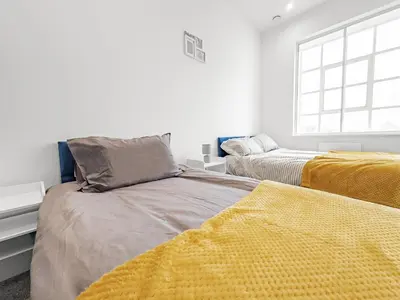 a white room with two beds and a window at Bright & Cozy in Chelmsford in Chelmsford