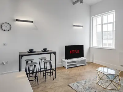 a living room with a table and stools and a tv at Bright & Cozy in Chelmsford in Chelmsford