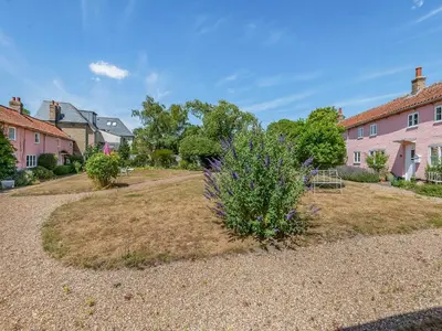 a house with a yard with a flowering plant at The Pink Cottage