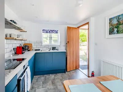 a kitchen with blue and white counters and a table at The Pink Cottage