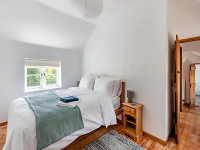 a white bedroom with a bed and a window at The Pink Cottage