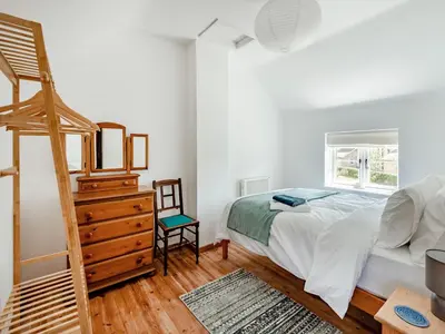 a bedroom with a bed and a wooden dresser at The Pink Cottage
