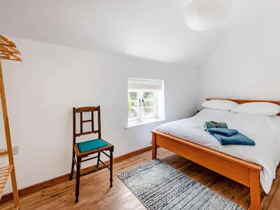 a bedroom with a bed and a chair at The Pink Cottage