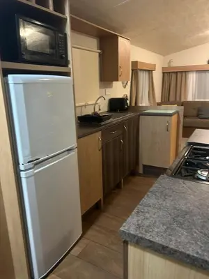 a kitchen with a white refrigerator and a microwave at 2 bed caravan seawick hoilday Park in Clacton-on-Sea