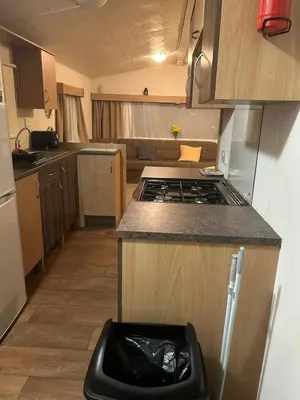 a small kitchen with a stove and a trash can at 2 bed caravan seawick hoilday Park in Clacton-on-Sea