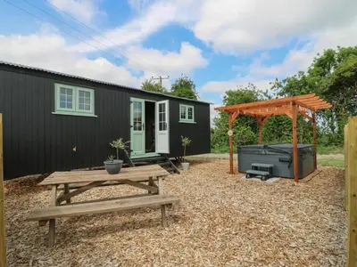 a backyard with a picnic table and a black house at Luxury Shepherd Hut with Private Hot Tub in Swaffham Bulbeck