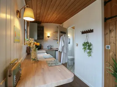 a kitchen with a wooden table and a kitchen with a sink at Luxury Shepherd Hut with Private Hot Tub in Swaffham Bulbeck