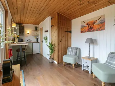 a living room with a cow picture on the wall at Luxury Shepherd Hut with Private Hot Tub in Swaffham Bulbeck