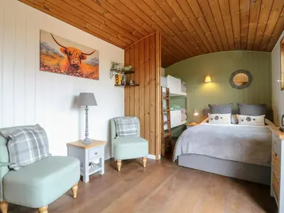 a bedroom with a bed and a chair at Luxury Shepherd Hut with Private Hot Tub in Swaffham Bulbeck