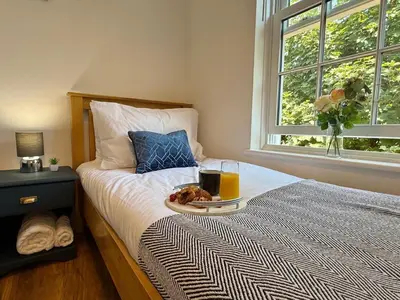 a bed with a plate of food and a glass of orange juice at 2 bed Elegant Flat in Stansted with parking in Stansted Mountfitchet