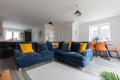 a blue couch with yellow pillows in a living room at Beaulieu Rest 3 Bed House Chelmsford in Broomfield