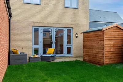 a house with a patio with two couches in the grass at Beaulieu Rest 3 Bed House Chelmsford in Broomfield