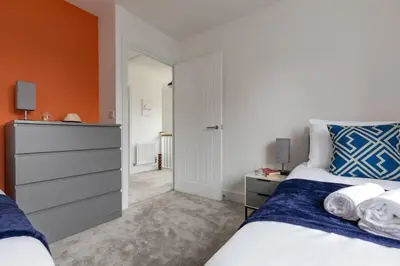 a bedroom with a bed and an orange wall at Beaulieu Rest 3 Bed House Chelmsford in Broomfield