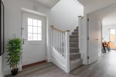 a white hallway with a staircase and a white door at Beaulieu Rest 3 Bed House Chelmsford in Broomfield