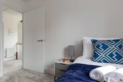a bedroom with a bed with blue and white pillows at Beaulieu Rest 3 Bed House Chelmsford in Broomfield