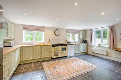 a large kitchen with white cabinets and a clock on the wall at 4 Bed in Hartest oc-w32685 in Hartest