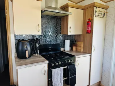 a kitchen with white cabinets and a stove top oven at Cosy 2 bed in Dovercourt Holiday Park -Sleeps 6 in Harwich