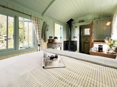 a bedroom with a bed with a magazine on it at The Hollies Shepherds Hut by The Suffolk Cottage Collection in Sutton