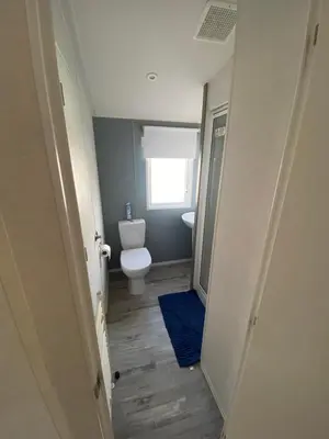 a bathroom with a toilet and a blue rug at Seawick Holiday Park in Saint Osyth