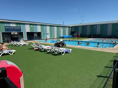a pool with lawn chairs and people in the water at Seawick Holiday Park in Saint Osyth