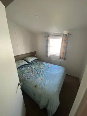 a small bedroom with a bed and a window at Seawick Holiday Park in Saint Osyth