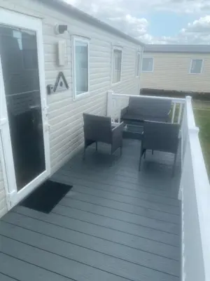 a large deck with two chairs and a table at Seawick Holiday Park in Saint Osyth