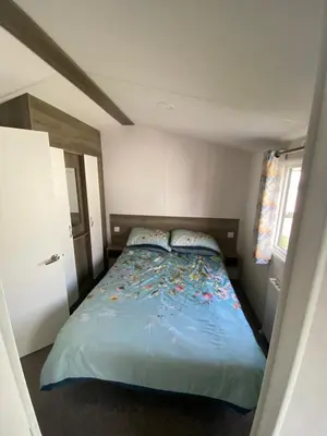 a bedroom with a bed with a blue comforter at Seawick Holiday Park in Saint Osyth