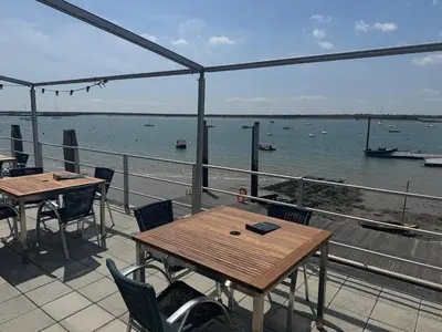 a balcony with tables and chairs and a view of the water at Rural Retreats 8 in Southminster