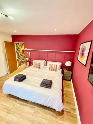 a bedroom with a large white bed with a red wall at Beautiful city centre studio - central location in Cambridge