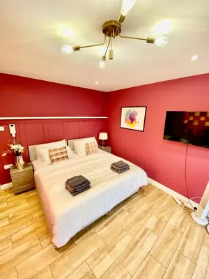 a bedroom with a large bed with a red wall at Beautiful city centre studio - central location in Cambridge