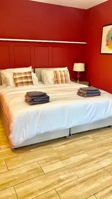 a large bed in a bedroom with a red wall at Beautiful city centre studio - central location in Cambridge