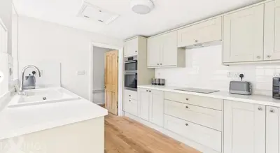 a white kitchen with white cabinets and a sink at Courtyards, 9 Mount street,Diss in Diss