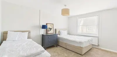 a white bedroom with two beds and a window at Courtyards, 9 Mount street,Diss in Diss